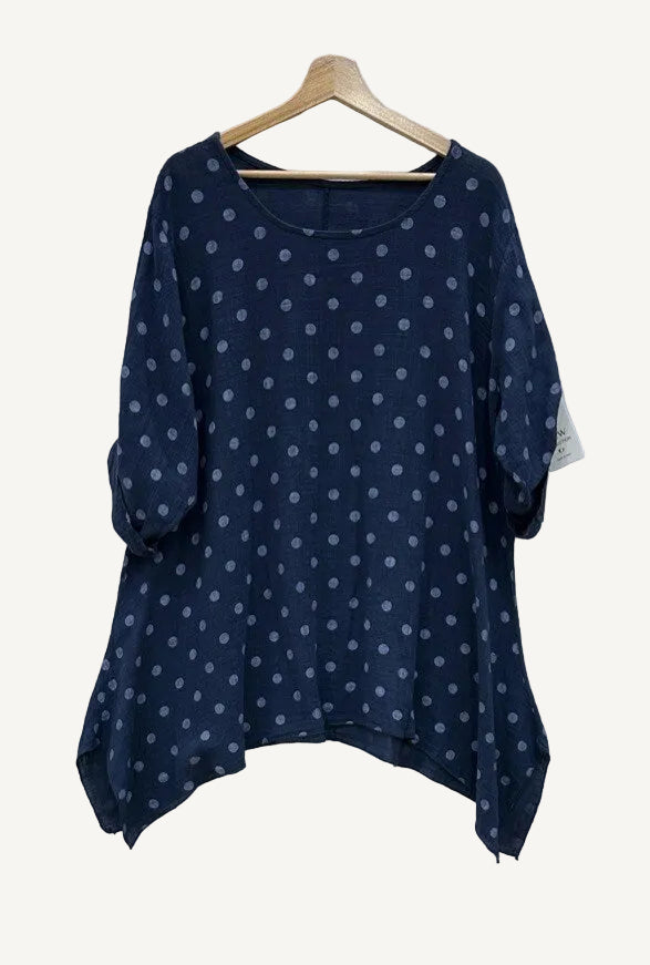 Navy blue blouse with white polka dots on a wooden hanger 