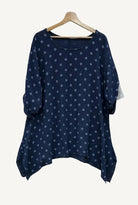 Navy blue blouse with white polka dots on a wooden hanger 