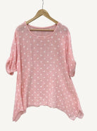 Pink polka dot shirt on a hanger against a light gray background