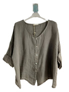 A woman wearing a taupe one size pure linen button fronted collarless shirt with three quarter sleeves.