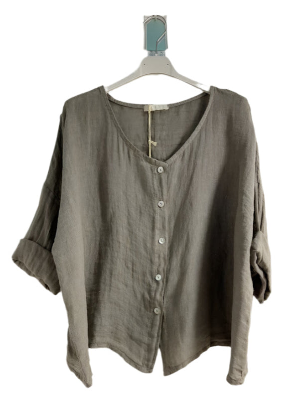 A woman wearing a taupe one size pure linen button fronted collarless shirt with three quarter sleeves.