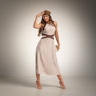 A woman modeling a sleeveless taupe midi dress with a brown contrast detail and shirred back