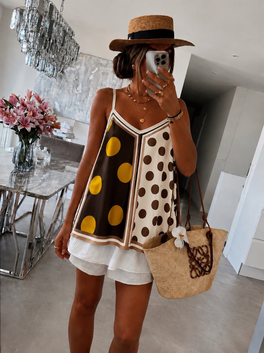 Person wearing a polka dot dress with a straw bag in a modern interior setting