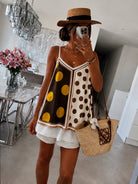 Person wearing a polka dot dress with a straw bag in a modern interior setting