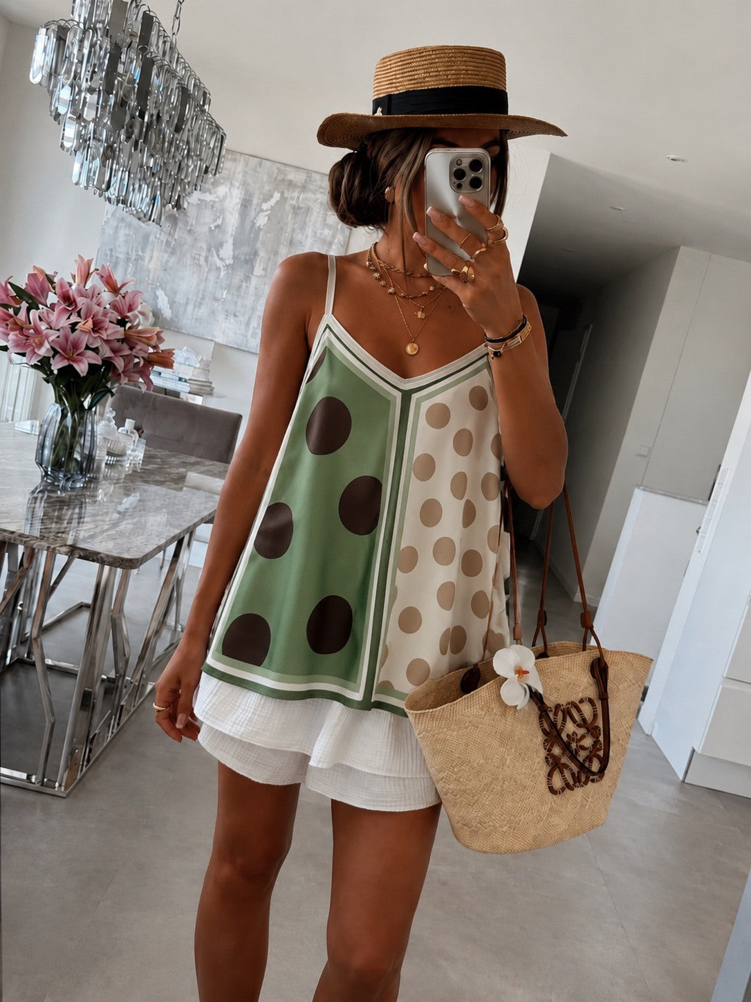 Person wearing a polka dot dress with a straw bag in a modern interior setting