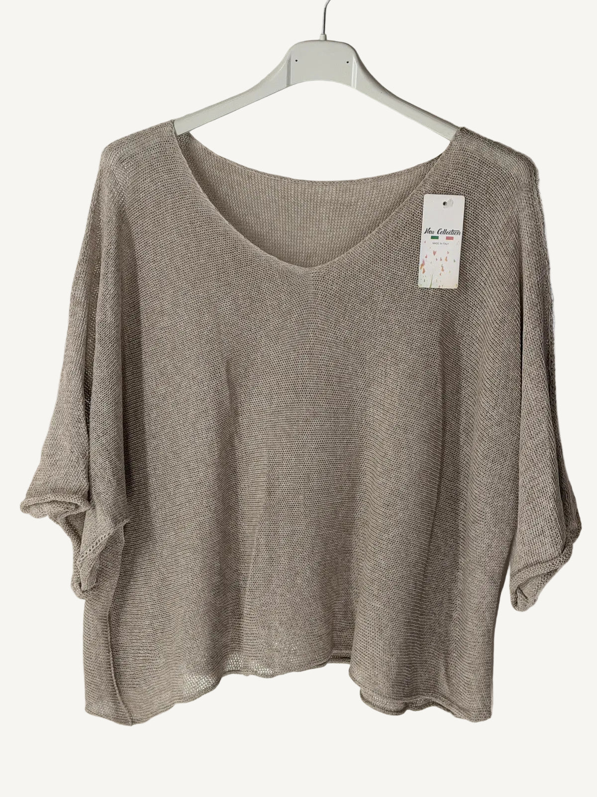 Brown sweater on a hanger with a tag against a textured wall.