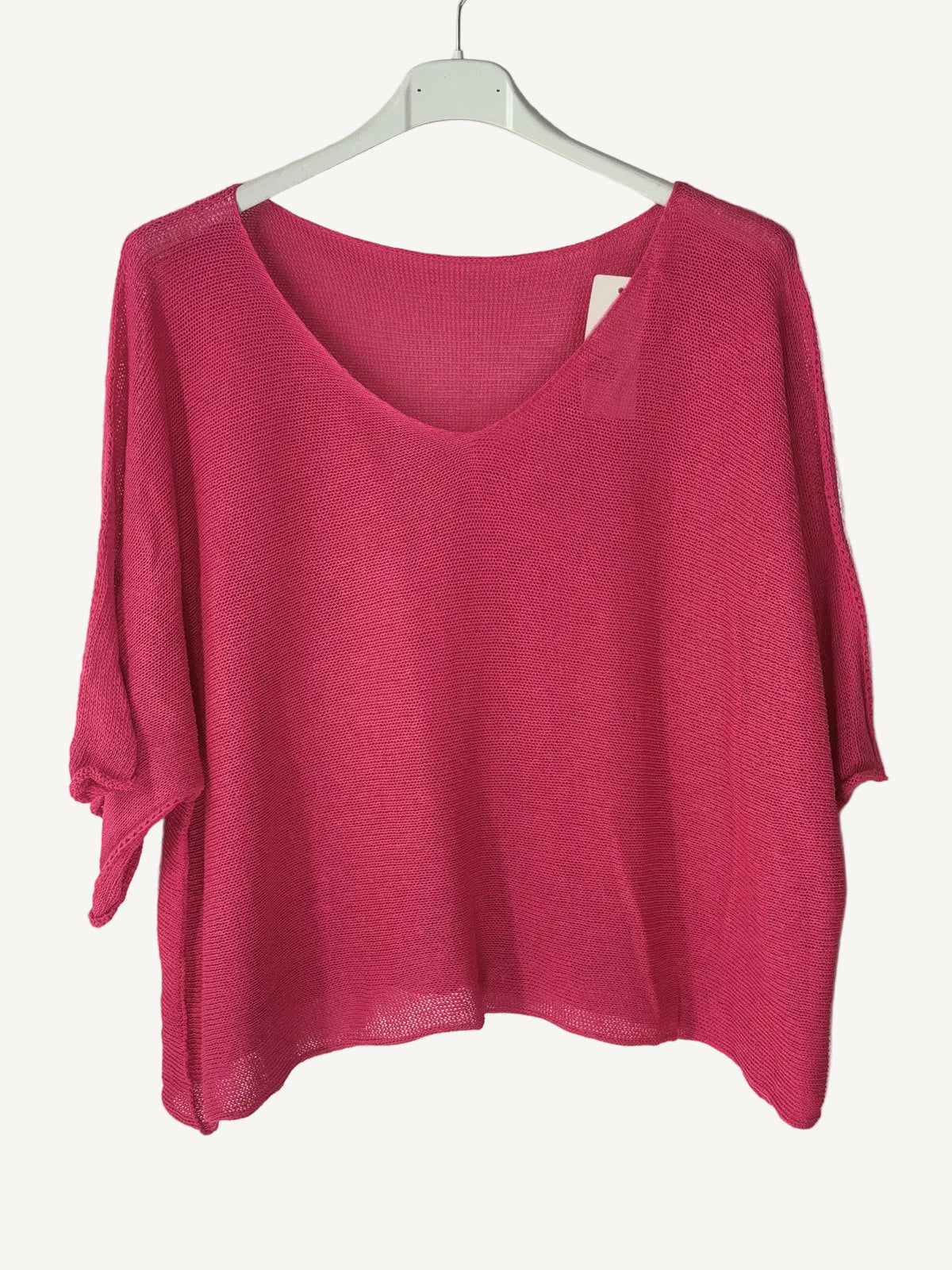 Pink sweater on a hanger against a light  wall