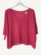 Pink sweater on a hanger against a light  wall