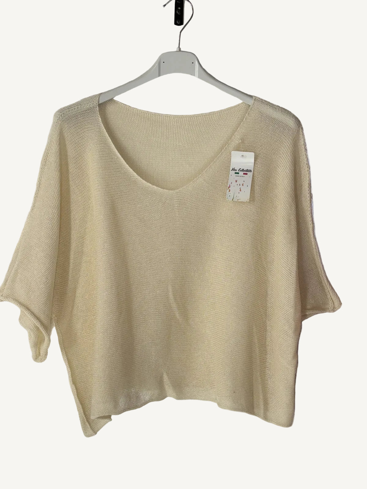 Beige sweater on a hanger against a beige wall