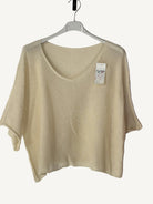 Beige sweater on a hanger against a beige wall