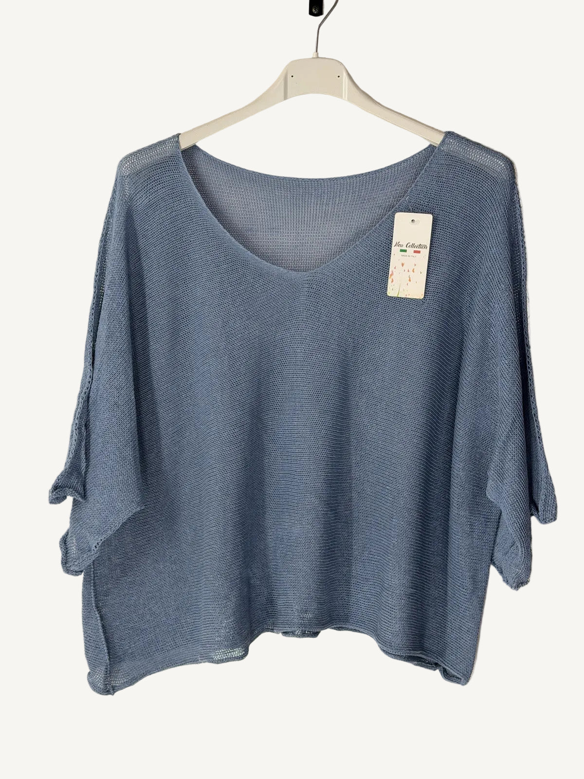 Blue sweater on a hanger with a beige background