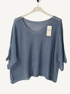 Blue sweater on a hanger with a beige background
