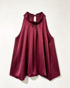 A sleeveless, high-neck top in a deep burgundy satin fabric, displayed flat against a light off-white background.