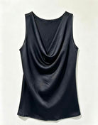 A sleeveless black cowl neck top with a draped, gathered silhouette, displayed flat against a light off-white background.