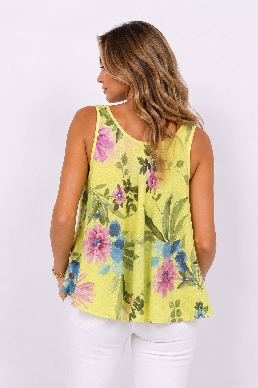 Woman wearing a yellow floral sleeveless top against a white background