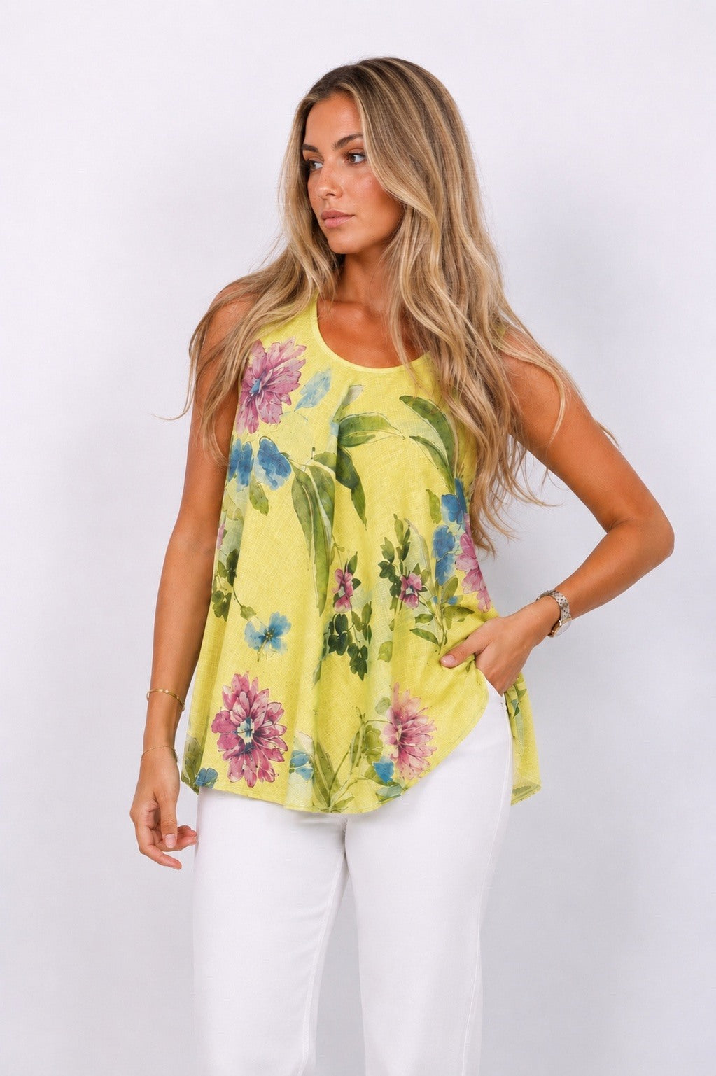 Woman wearing a yellow floral sleeveless top against a white background