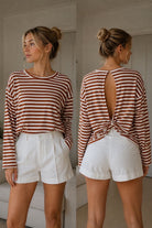 A woman modeling a long-sleeve striped top and white shorts in a split front-and-back view.