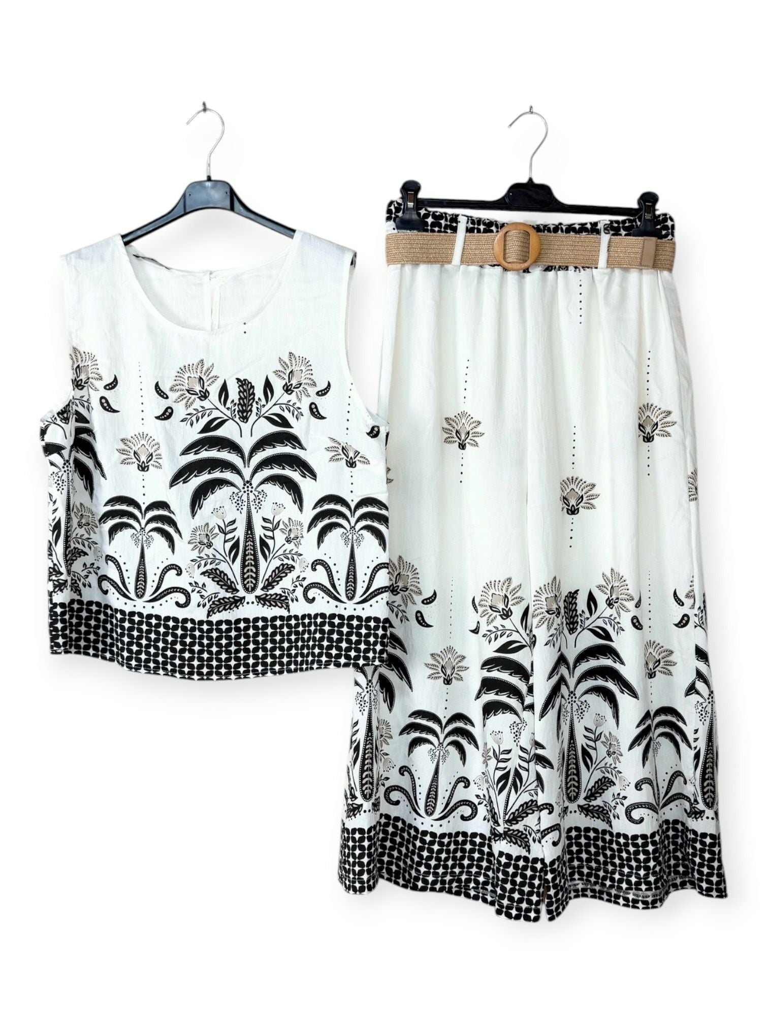 White top and skirt set with black floral patterns on hangers against a white background