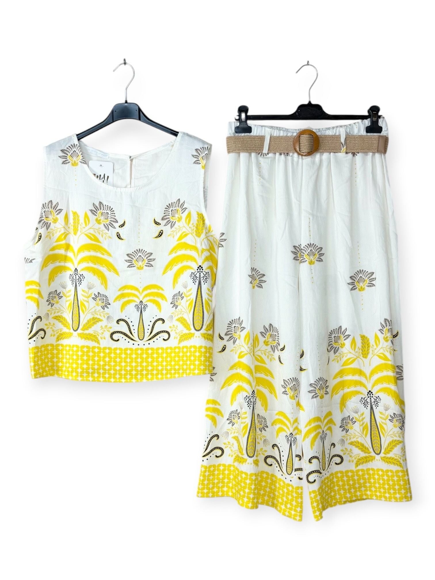 White outfit with yellow floral patterns on hangers against a white background
