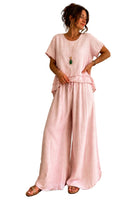 Woman wearing a pink outfit standing in front of a white background.