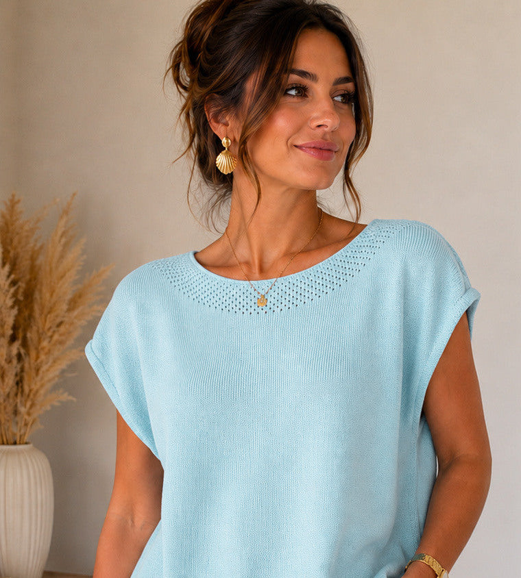 Woman wearing a light blue top and white pants, with product details displayed.