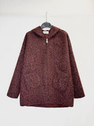A textured, marled burgundy zip-up hoodie jacket hanging on a black hanger against a plain white wall.