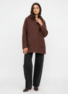 A woman modeling a brown textured hooded jacket with black wide-leg jeans and brown boots