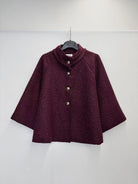 A dark burgundy textured jacket with a mock neck and three silver buttons, hanging on a black hanger against a plain white wall.