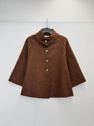 A brown textured bouclé jacket with a mock neck and three front buttons, hanging on a black hanger against a plain white wall.