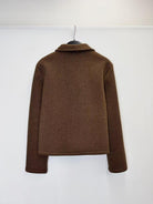 A brown long-sleeve knit top or sweater shown from the back, hanging on a black hanger against a plain white wall.