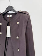 A dark brown double-breasted jacket with silver buttons, hanging on a black hanger with a white brand tag against a plain white background.