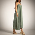 A woman modeling a green linen maxi dress with studded shoulder straps and a smocked bodice