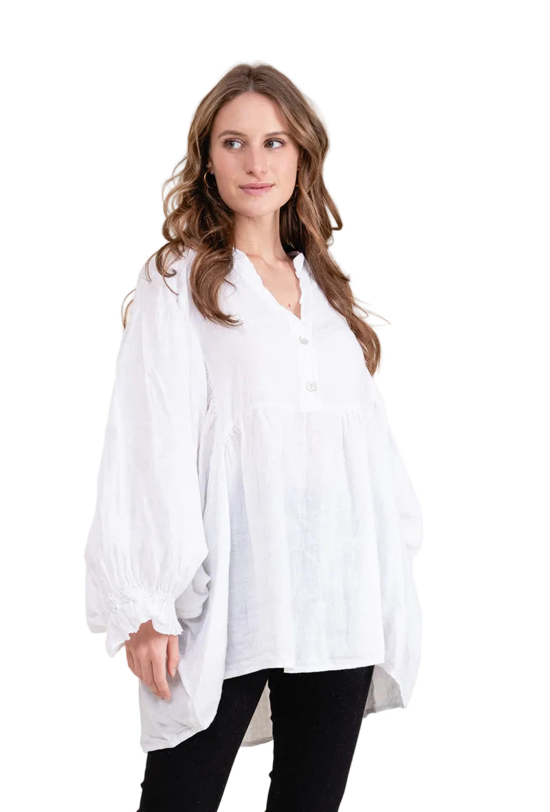 Woman wearing a white oversized shirt against a beige background