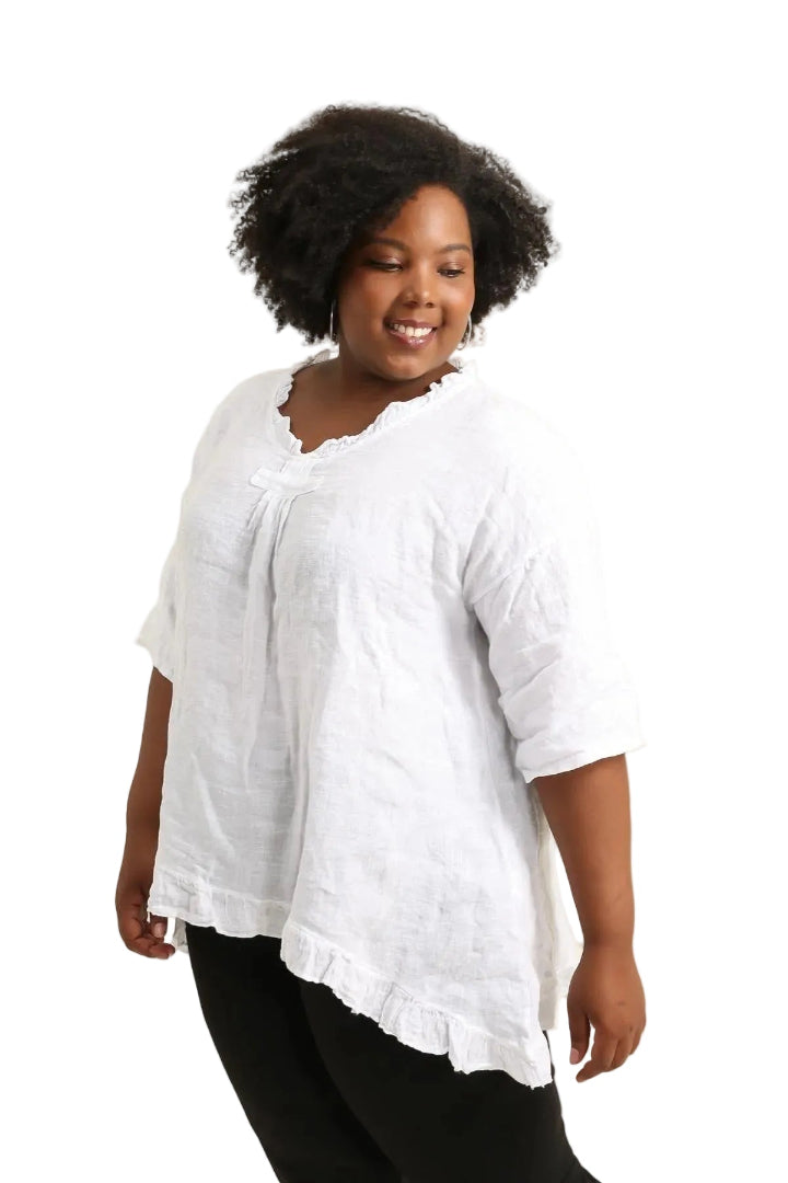 Woman wearing a white textured top and black pants on a white background