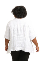 Person wearing a white linen top on a white background