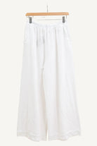 White wide-leg pants on a hanger against a white background