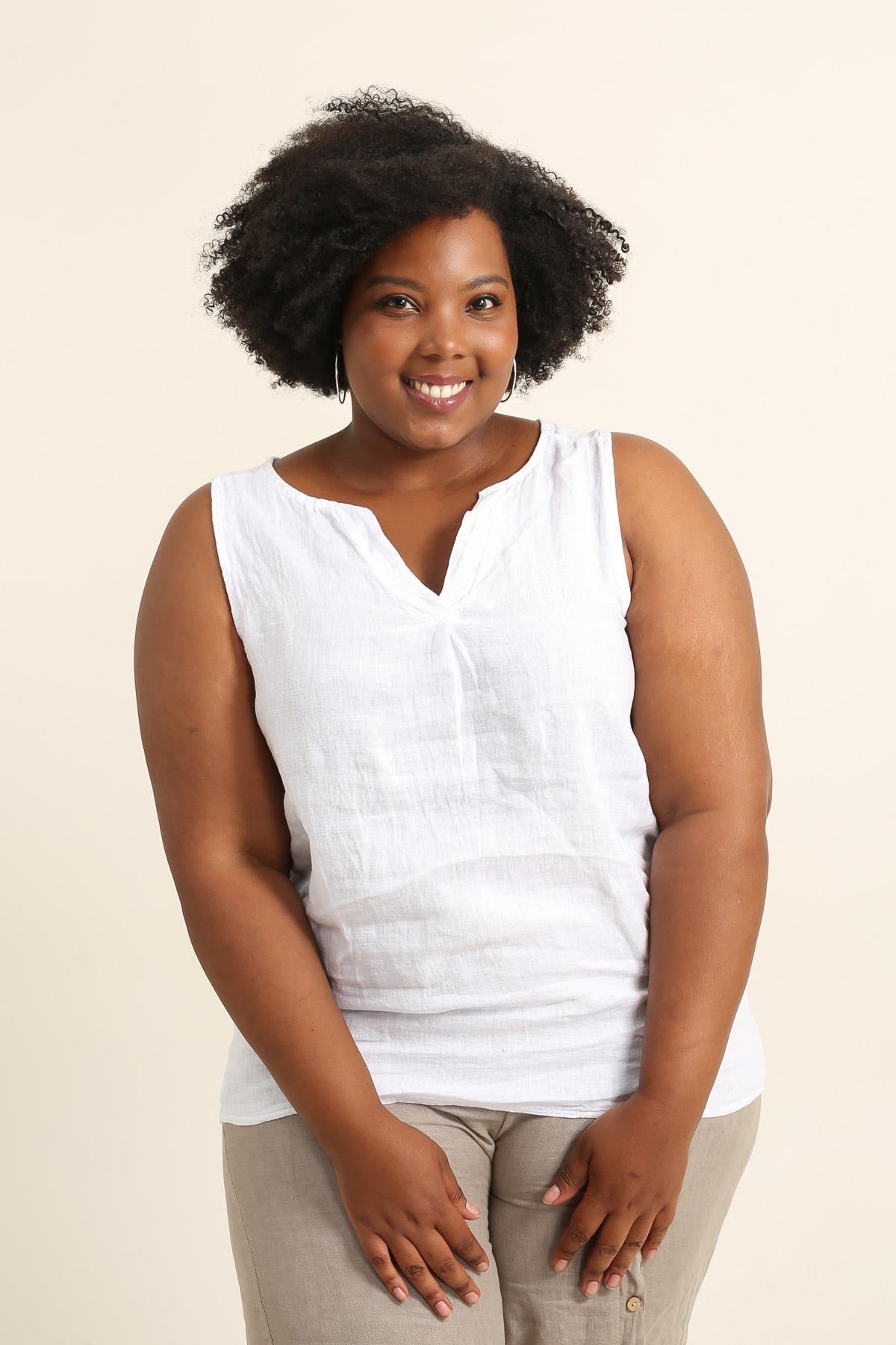 Woman wearing a white sleeveless top against a beige background