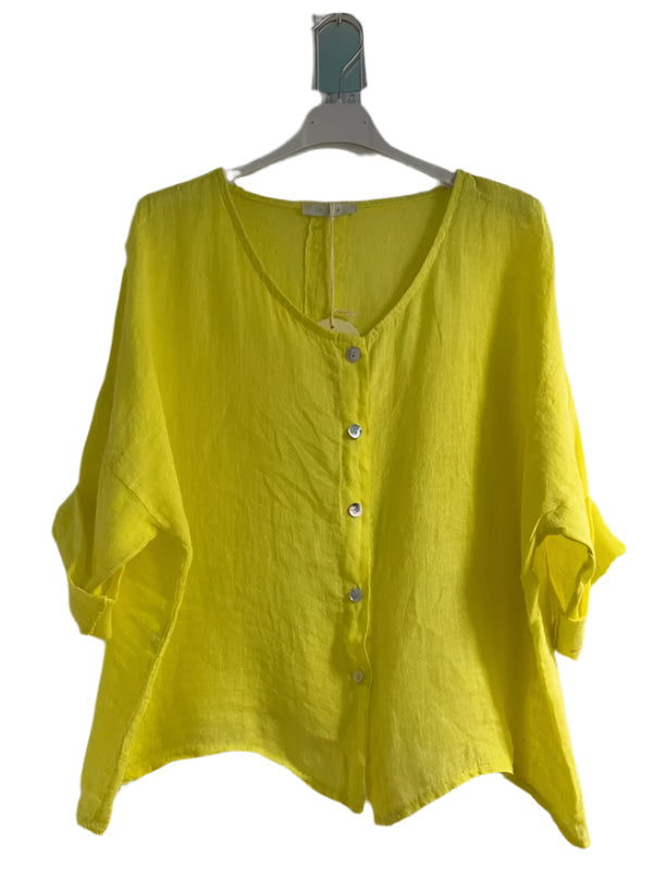 A woman wearing a yellow one size pure linen button fronted collarless shirt with three quarter sleeves.