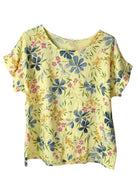 A pale yellow short-sleeve top with a blue, pink, and green floral print, displayed flat against a white background.