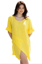 A woman wearing a yellow asymmetrical linen tunic top with three-quarter sleeves.