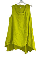 A woman wearing a lime green sleeveless cowl neck top with an asymmetrical hem, paired with white trousers.