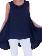 A woman wearing a navy blue sleeveless cowl neck top with an asymmetrical hem, paired with white trousers.