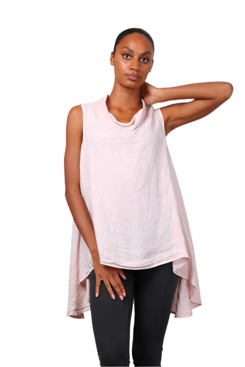 A woman wearing a pink sleeveless cowl neck top with an asymmetrical hem, paired with white trousers.