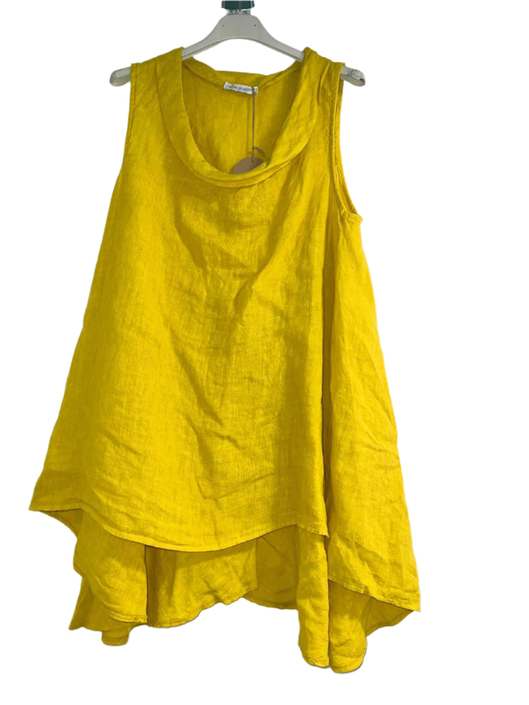 A woman wearing a yellow sleeveless cowl neck top with an asymmetrical hem, paired with white trousers.